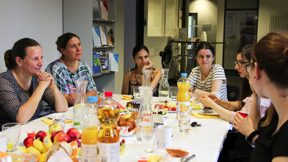 Prof. Tanja Zseby is sitting at the table with with female scientists and students