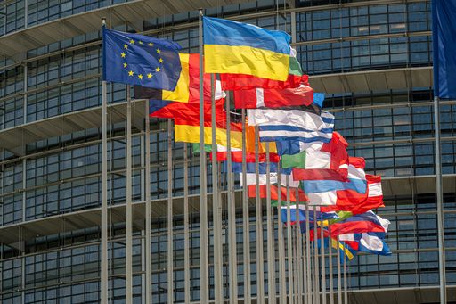 Flags of the EU member states in front of an EU building.