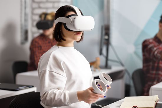 A woman wears VR goggles and holds a kind of joystick in her hand 