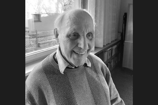 Porträtbild Gerhard Jangg in s/w mit schwarzen Balken links und rechts. Aufgenommen in einem privaten Raum.