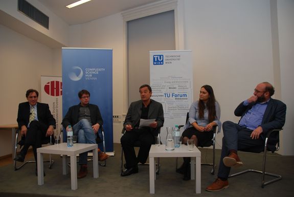 View of the podium. From left to right: Radu Groso, Peter Klimek, Norbert Fiala (presenter), Olga Saukh and Niki Popper. In the background is a roll-up of the Clompexity Science Hub and the TU Wien