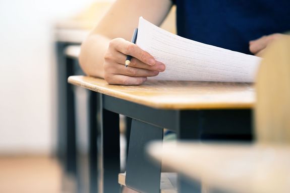 Person nur Oberkörper sitzend bei Tisch mit Zettel und Stift