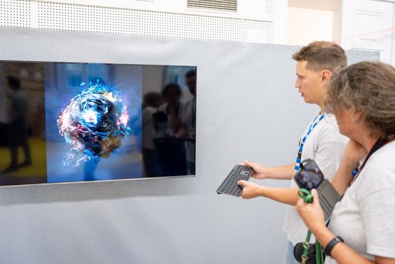 2 Menschen vor großem Monitor, darauf Erde als brennender Ball