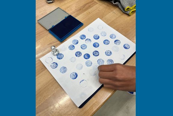 Hand stempelt mit selbstgemachten Stempeln in blau auf Papier