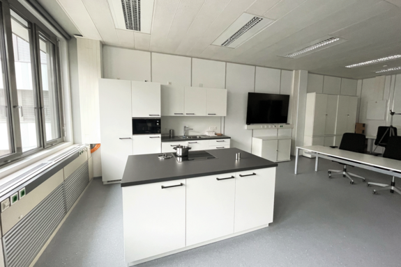 Schlichte Küche in Schwarz-Weiß mit Küchenblock in der Mitte.