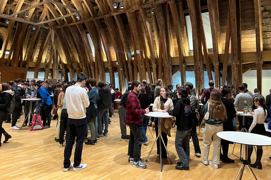 Personen stehen an Tischen zusammen.