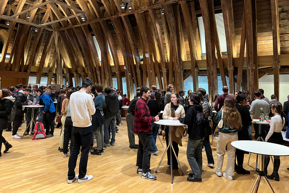 Personen stehen an Tischen zusammen.