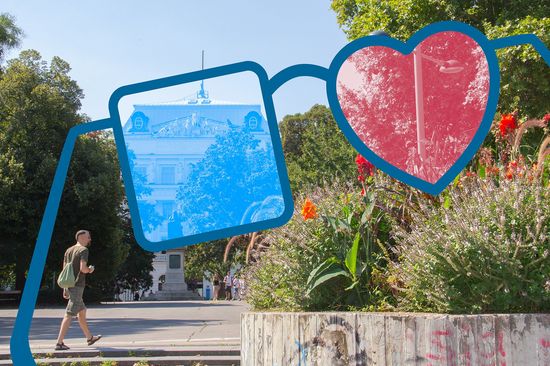 Hauptgebäude mit Bäumen, im Vordergrund Brille in groß, rechtes Glas quadratisch in blau, linkes Glas herzförmig in rot
