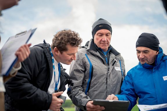 Drei Personen schauen auf Tablet.