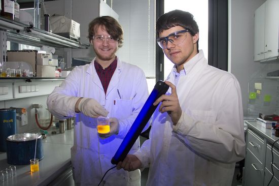 Fabian Zechmeister (links) und Maximilian Raab (rechts) demonstrieren die Fluoreszenz einer Perylenbisimidlösung