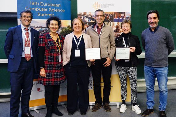 6 Personen stehen nebeneinander und präsentieren die Urkunde