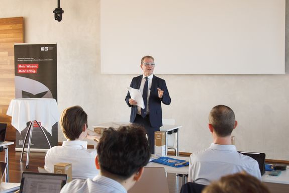 Lehrgangsleiter Bob Martens steht im Vortragsraum und begrüßt die neuen Studierenden