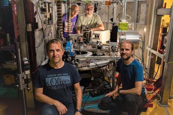 four people in a lab with technical equipment between them