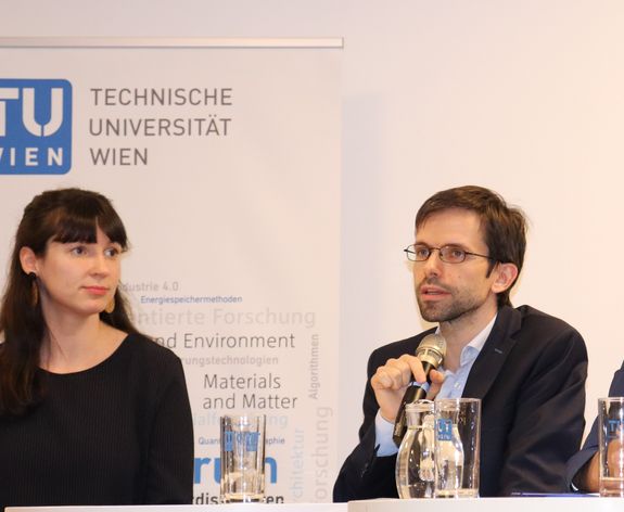 A close-up of Susanne Kaiser and Alexander Schirrer. Alexander Schirrer speaks into the microphone.