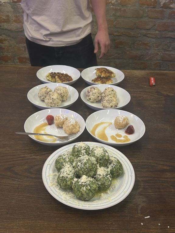 Man sieht 6 kleine Teller - zweireihig aufgestellt, davor ist ein großer Teller. Auf allen Teller sind unterschiedliche Knödel platziert.