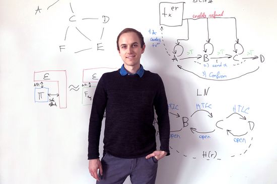 Lukas Aumayr in front of a white wall with formulas on it.