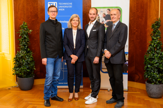 Gruppenfoto mit vier Personen vor Fahnen der TU Wien und der Pilotfabrik Industrie 4.0