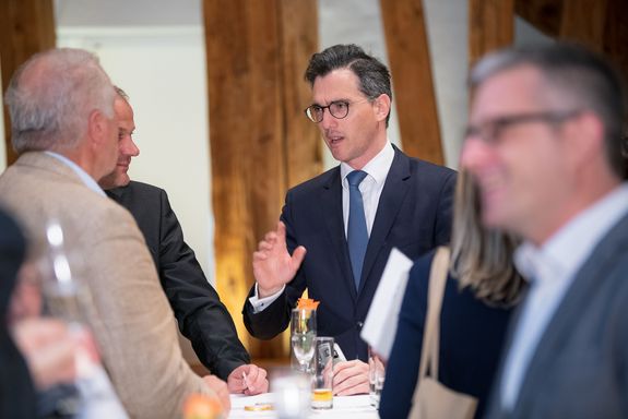 Bernhard Pichler stands with colleagues around a bar table and discusses.