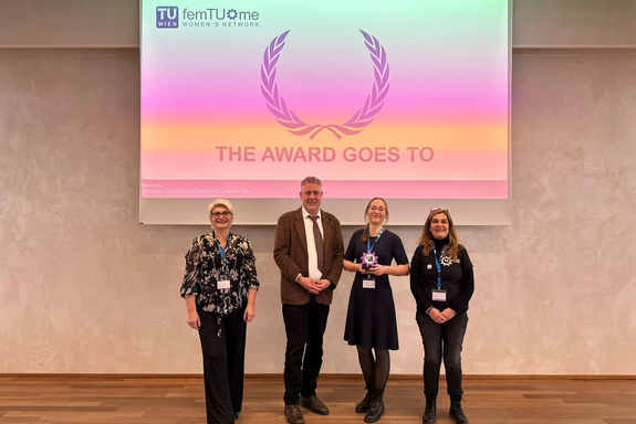 Group photo with 4 people. In the background a screen with the words “THE AWARD GOES TO”