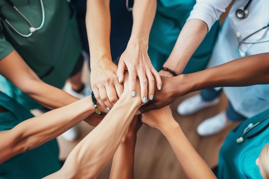 Several doctors with diverse backgrounds placing their hands together.