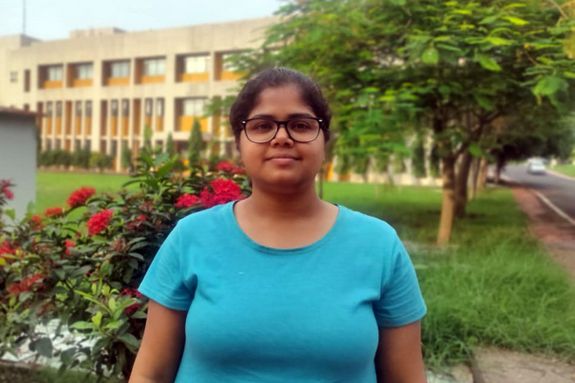 Portrait von Ruma Maity. Im Hintergrund Grünfläche und ein Gebäude.