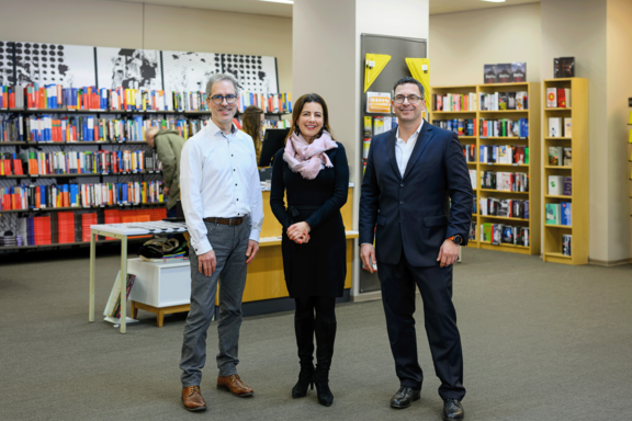 Gruppe mit drei Personen im INTU-Shop. Im Hintergrund Bücherregale.