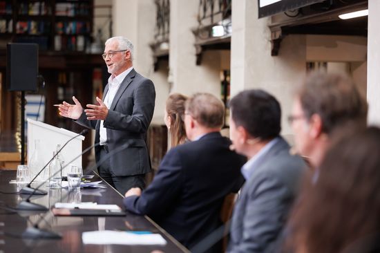 Speaker at speaker's desk, panelists watching