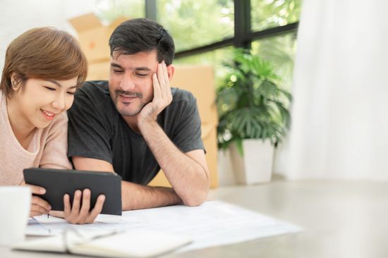 Ein diverses Paar schaut sich gemeinsam etwas auf einem Tablet an