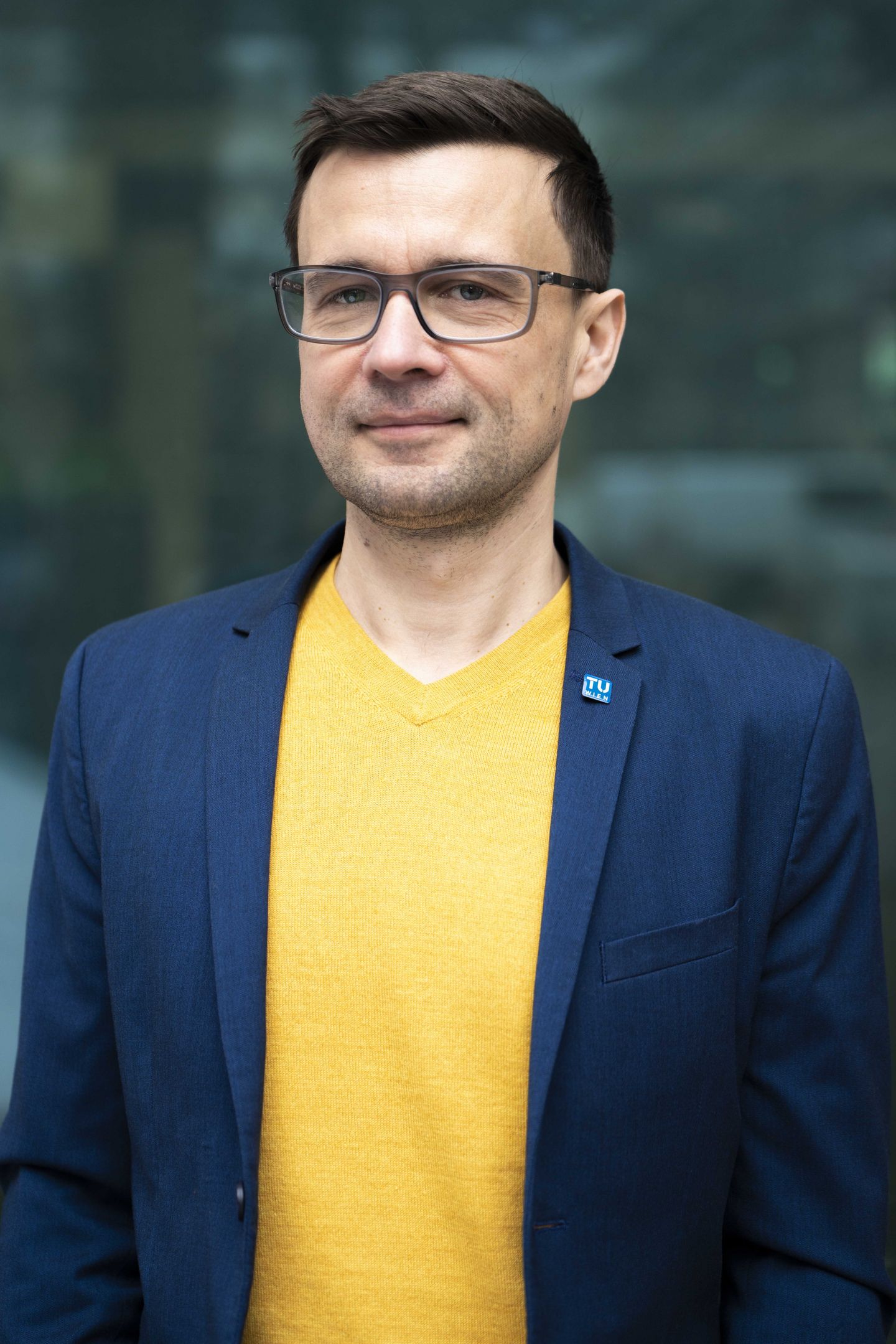 Porträt Michael Schnürch: Mann in gelben Shirt, darüber dunkle Jacke