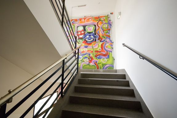 Grafitti im Stiegenhaus Farbige Graffiti auf der Wand im Stiegenhaus. Abbildung hat zwei mänliche gesichter in der Mitte.