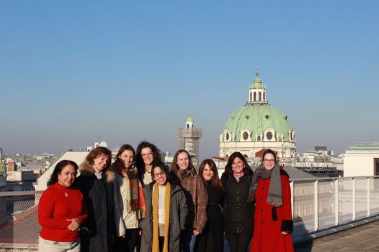 Group photo outdoors with a view of the green dome of St. Charles Church and a blue sky.