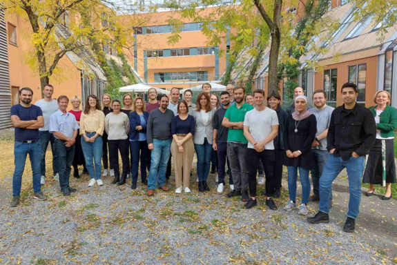 Eine Gruppe von Projektmitarbeiter_innen steht unter Bäumen im Innenhof eines Gebäudes der TU Graz.