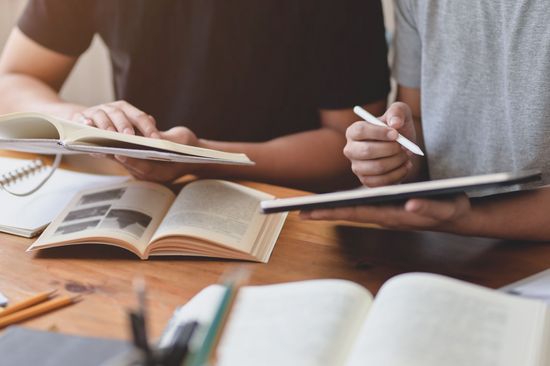 Zwei Studierende mit Büchern beim Lernen und Arbeiten.
