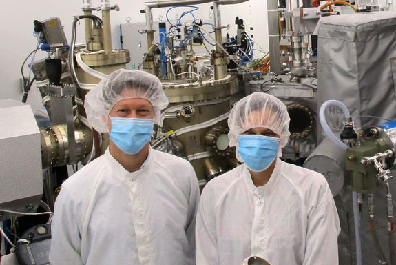 [Translate to English:] zwei Menschen mit Maske und Haarnetz im Reinraumlabor