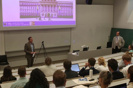 Personen sitzend und stehend im Hörsaal bei der Eröffnung