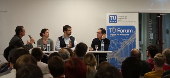 Blick auf das Podium aus dem Publikum. Von links nach rechts: Norbert Fiala (Moderator), Elisabeth Gruber, Florian Libisch und Thomas Müller