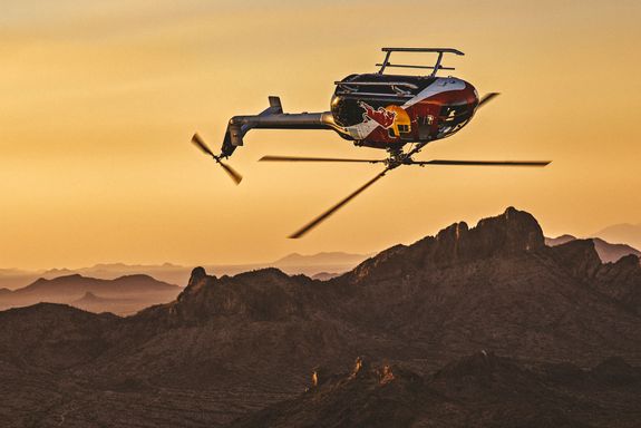 Hubschrauber fliegt auf dem Kopf über eine Berglandschaft.