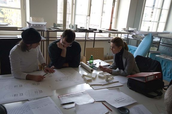 Three people discuss printed plans with each other