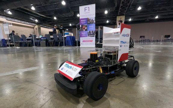 Ein Modell-Rennwagen auf einem Parkettboden in einem großen Saal