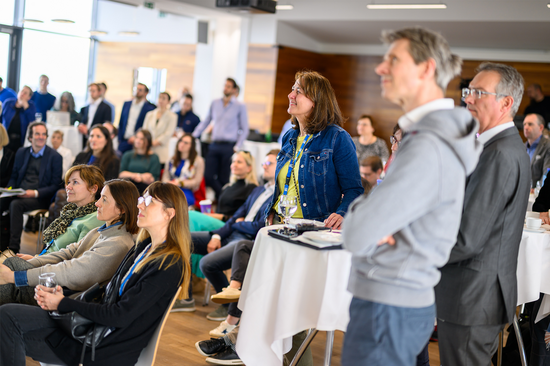 Zuhörer_innen, darunter Teile des TUW-Rektorats, an einem Stehtisch und in den Sitzreihen.