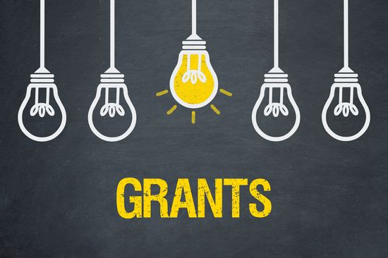 Von der Decke hängen 5 Glühbirnen, wobei die mittlere gelb leuchtet. Darunter steht "Grants"