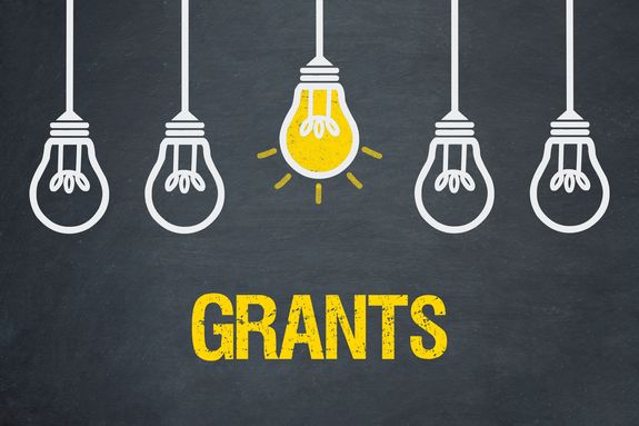 Von der Decke hängen 5 Glühbirnen, wobei die mittlere gelb leuchtet. Darunter steht "Grants"