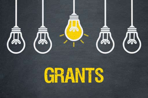 Von der Decke hängen 5 Glühbirnen, wobei die mittlere gelb leuchtet. Darunter steht "Grants"