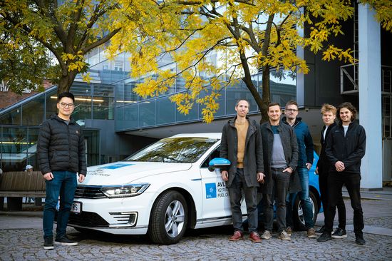 Sechs Männer stehen neben einem weißen Auto.