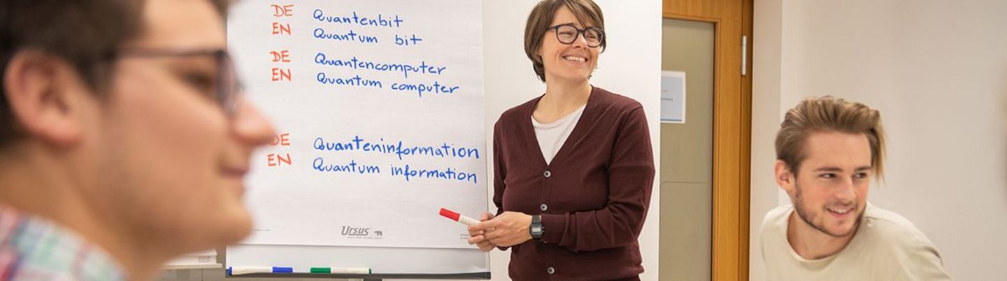 A teacher is explaining something written on a whiteboard.