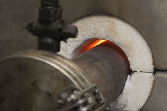 Kreisrunde Öffnung eines Klatwandofen. Drinnen sieht man Feuer.