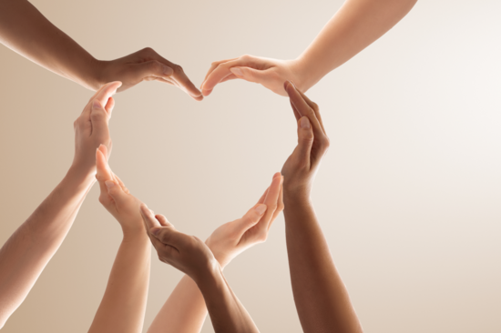 Seven hands are stretched into the picture and together form a heart