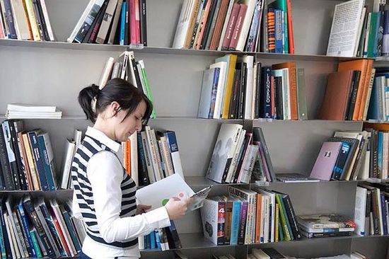 Reading person in front of bookshelf