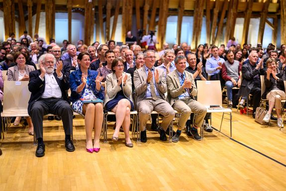 Publikum im Kuppelsaal der TUW. In der ersten Reihe das applaudierende Rektorat und Nobelpreisträger Zeilinger