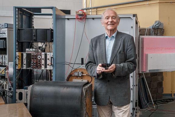 Prof. Helmut Rauch hält das Neutronen-Interferometer in den Händen. Im Hintergrund der Reaktor des Atominstituts. Foto: Nico Einsiedler